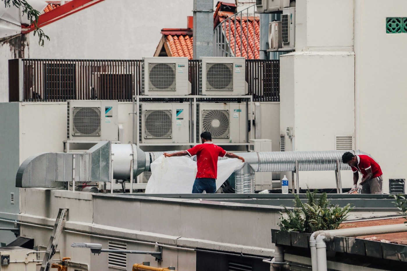 Two HVAC technicians servicing rooftop air conditioning units